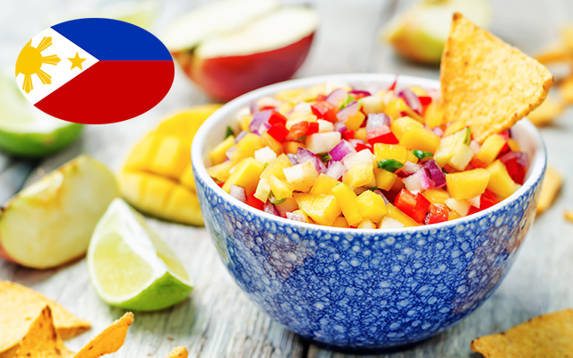 bowl of mango and tomato salsa in a bowl with a tortilla chip and lime wedges