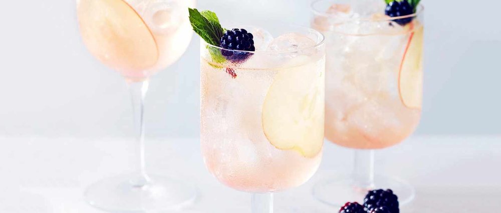 Pink blackberry cider fizz with apple slice and mint in goblets