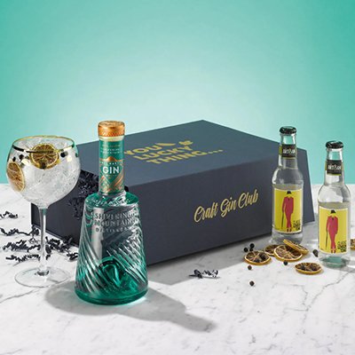 A bottle of gin and a G&T in a copa glass