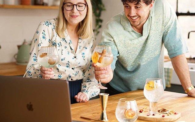 Two people making gin and tonics in front of their laptop