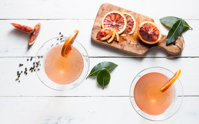 Blood orange martini gin drink with chopping board of dried oranges and bay leaves