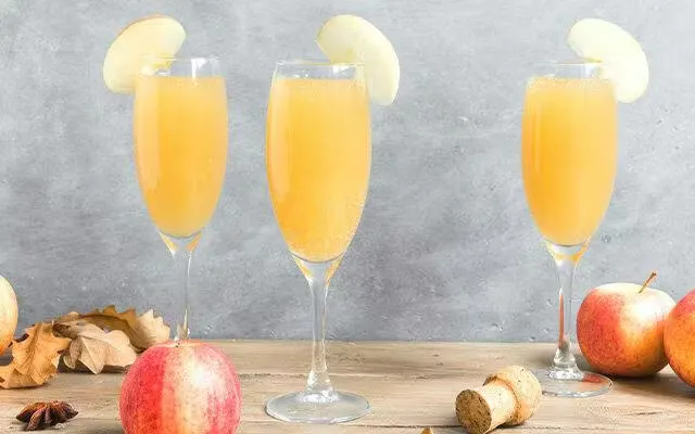 Three apple cocktails in champagne flutes and apple slice garnish