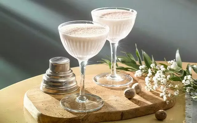 Two creamy white cocktails in coupe glasses with nutmeg sprinkled on top