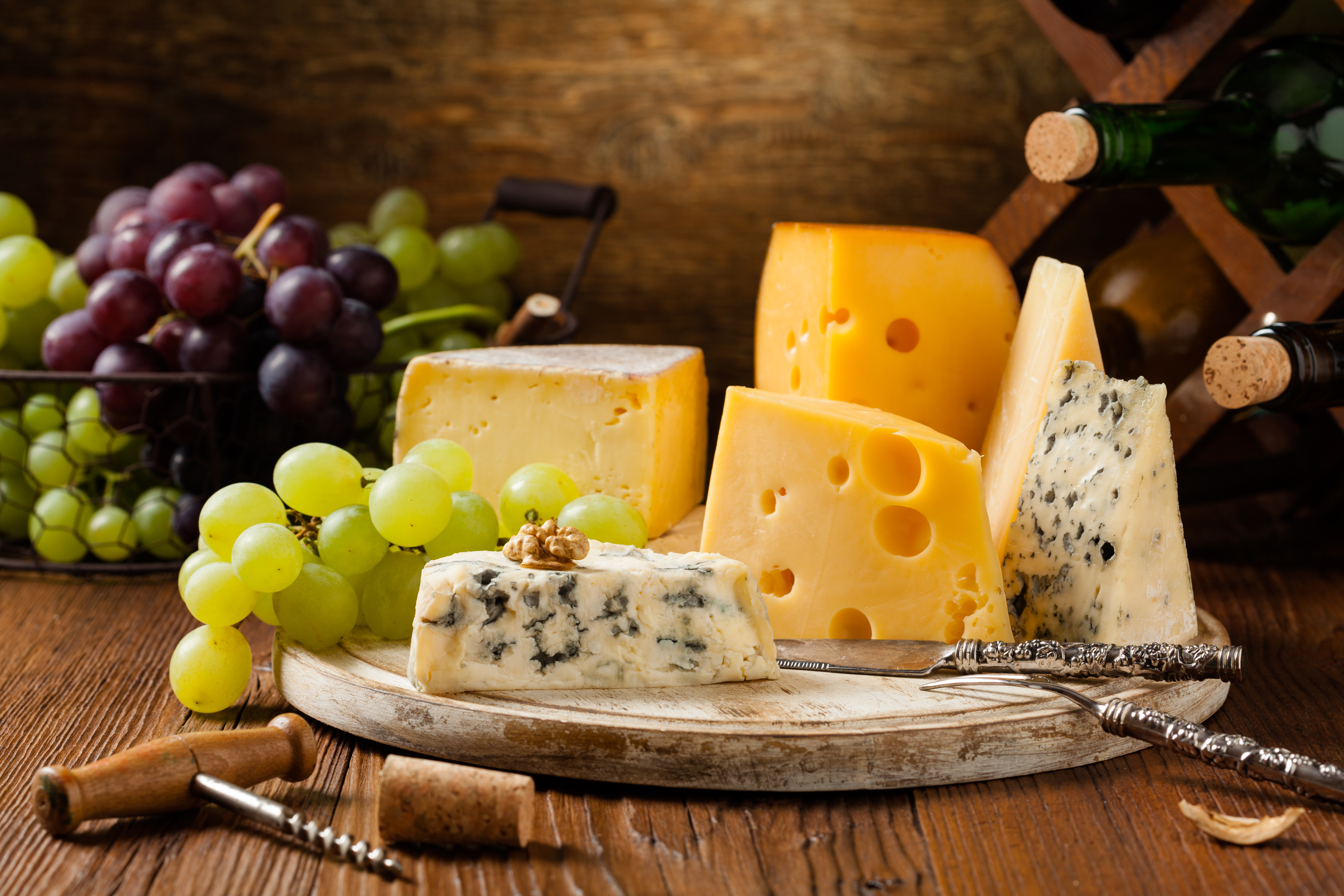 A variety of cheeses on a circular wooden cheeseboard