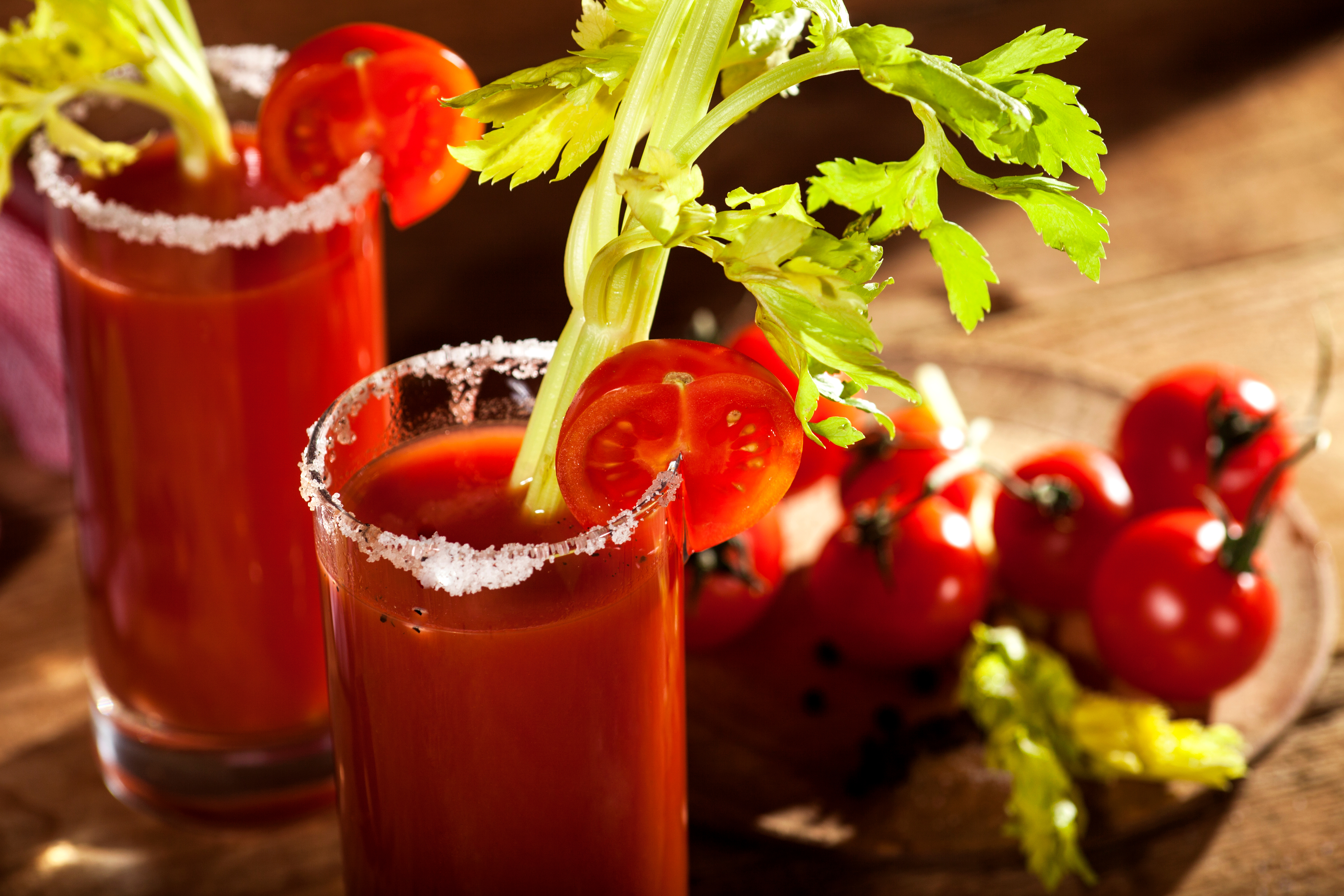 Close up of two Bloody Mary cocktails with a salt rim and tomato and celery garnish