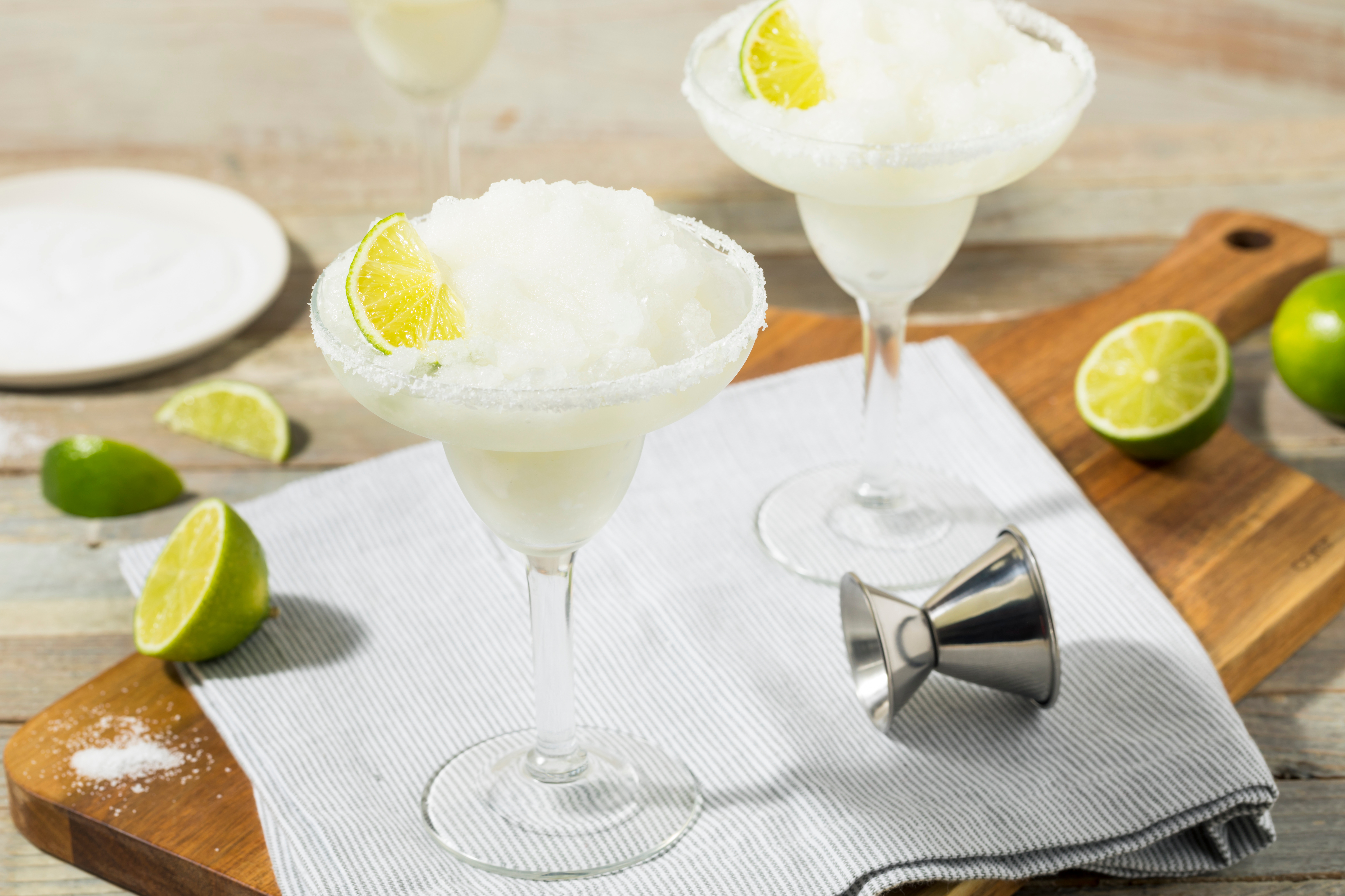 Two frozen cocktails on a wooden board with lemon garnish