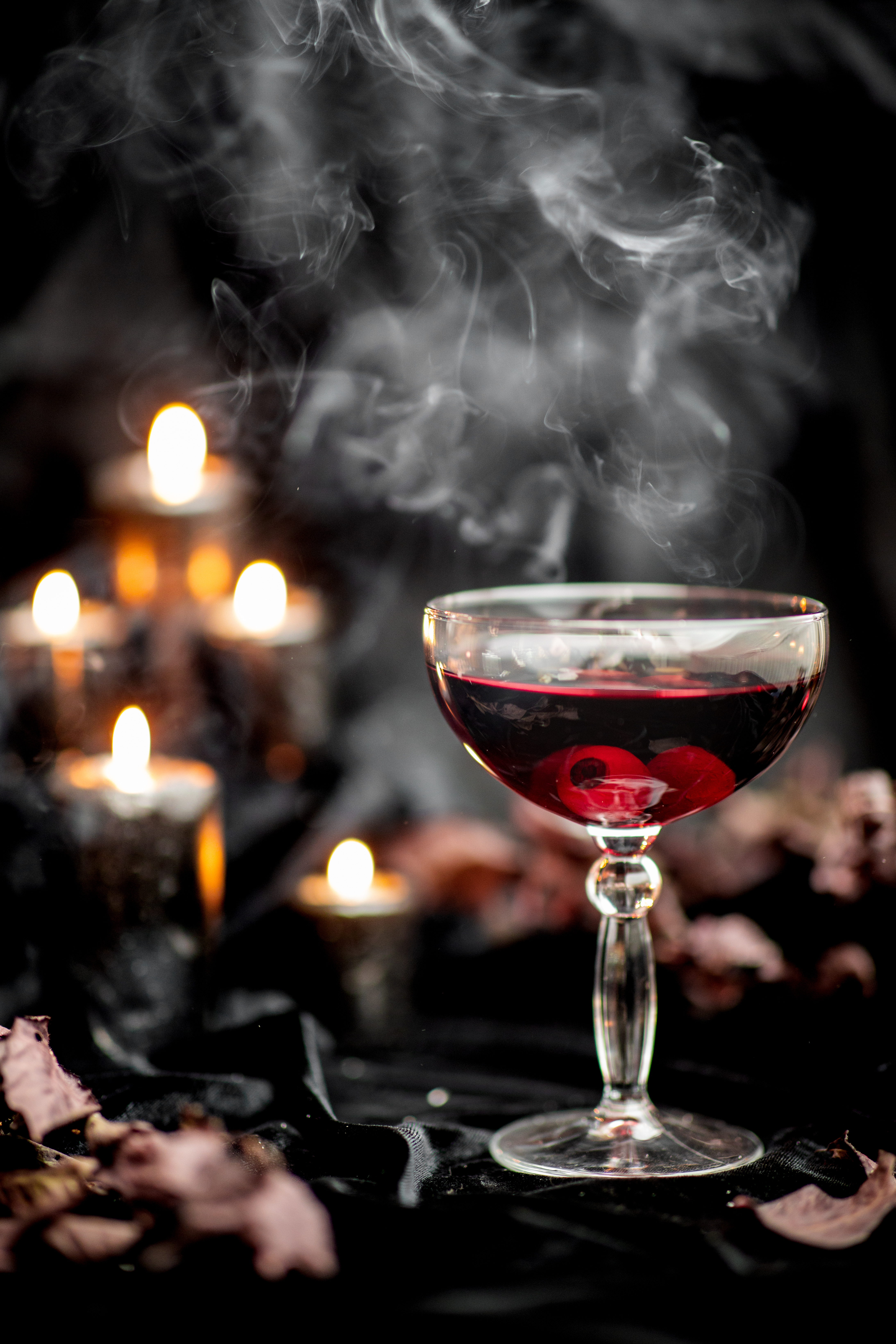 Deep red cocktail in coupe glass with a dark, smoky background