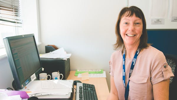 A Changing Lives staff member at her desk smiling at the camera
