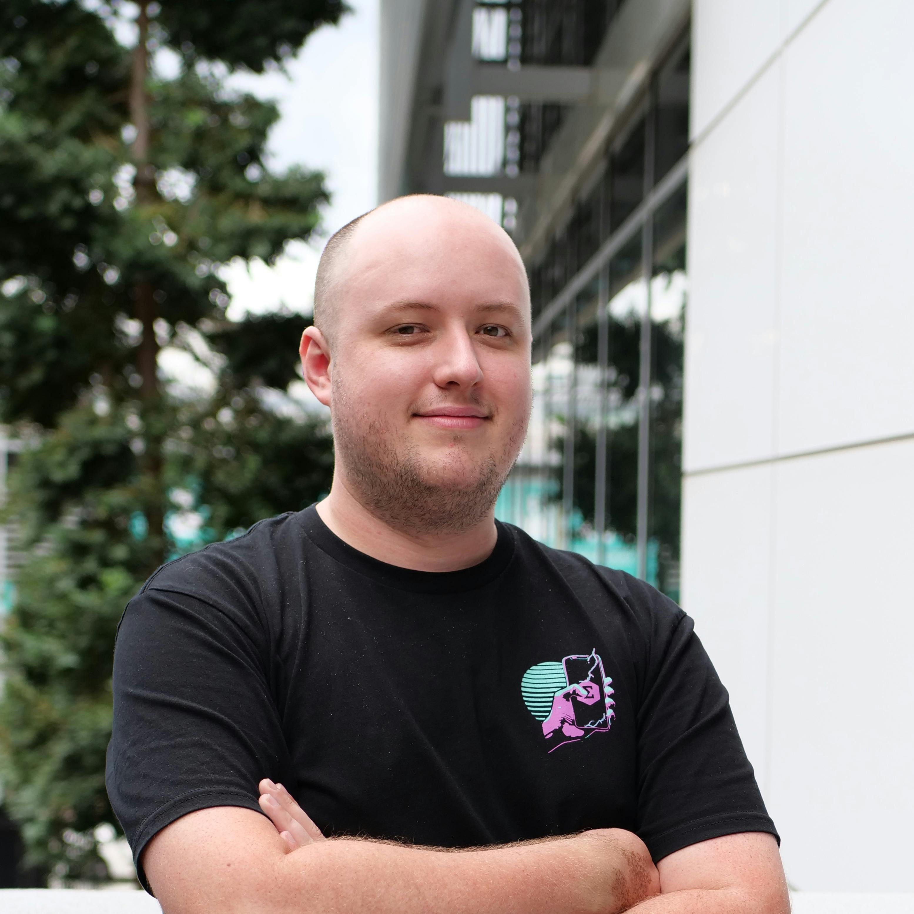 Charles Harwood standing next to a building, smiling with arms folded