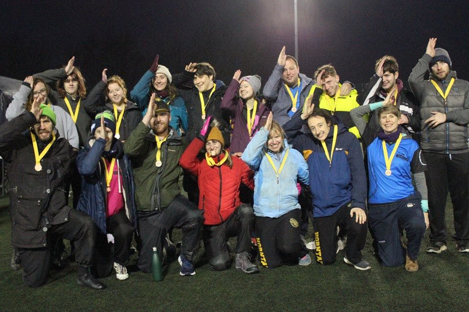 Megladons pose for a photo with their bronze medals, all making a "fin" sign on their heads