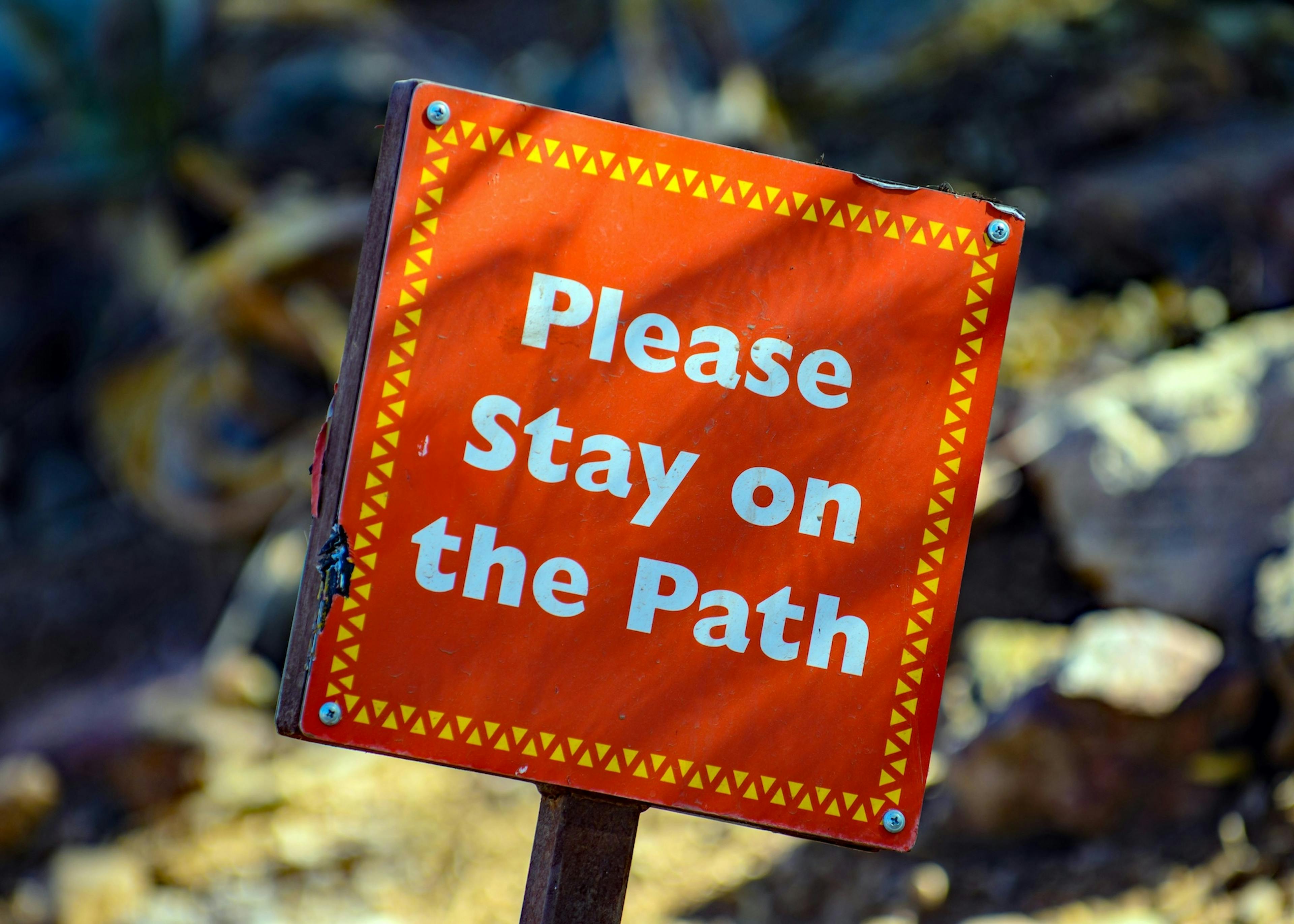 "please stay on the path" sign. Photo by Mark Duffel on Unsplash