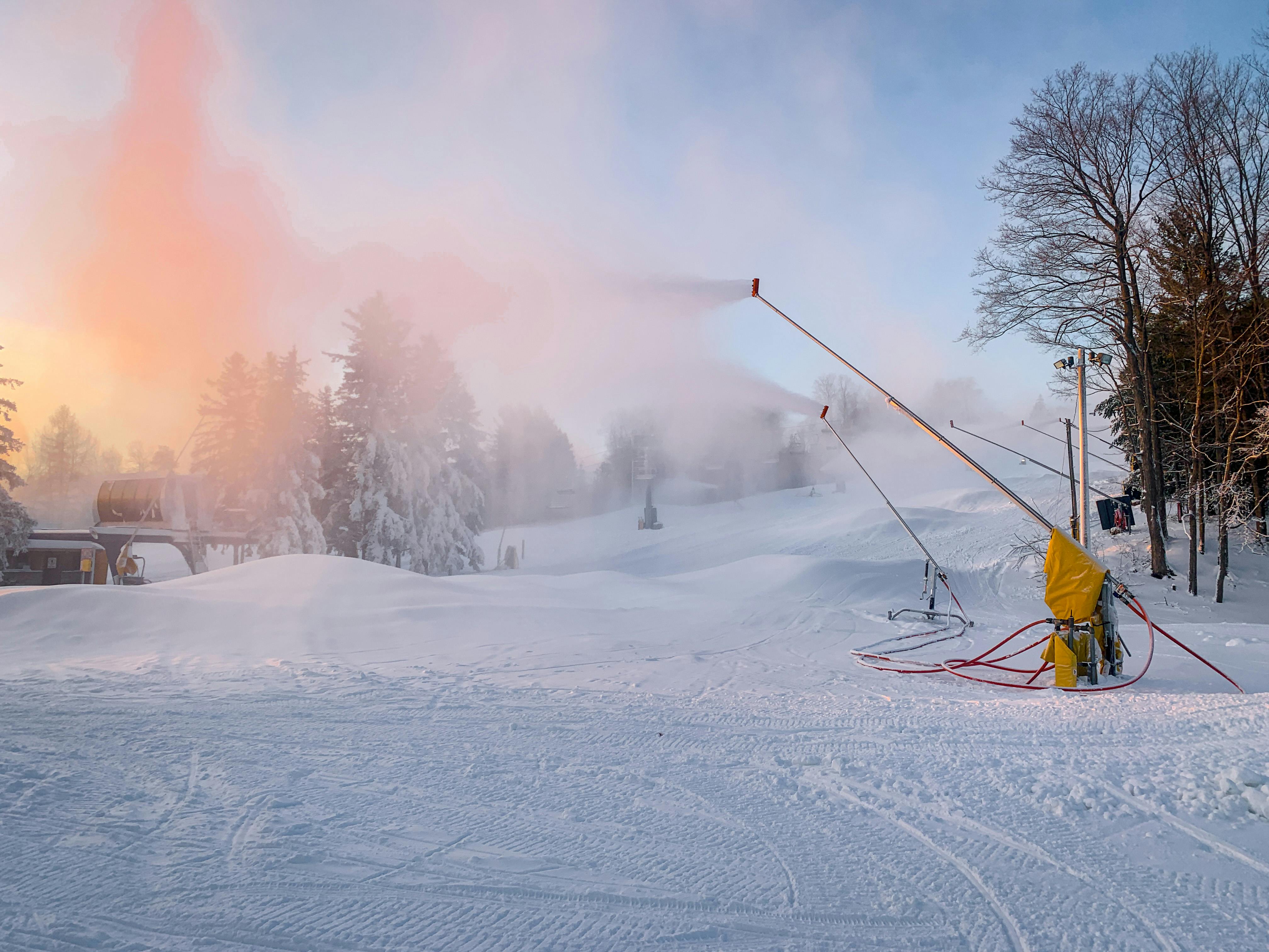 Snow guns blowing snow on North hill at dawn. 