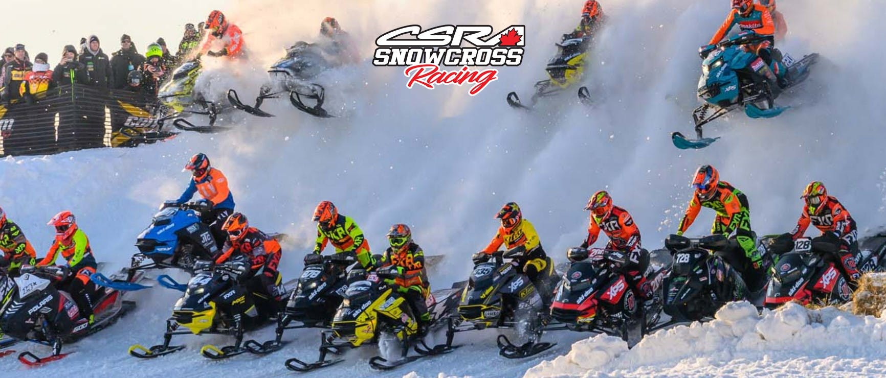 Snowmobile racers on their snowmobiles on course.