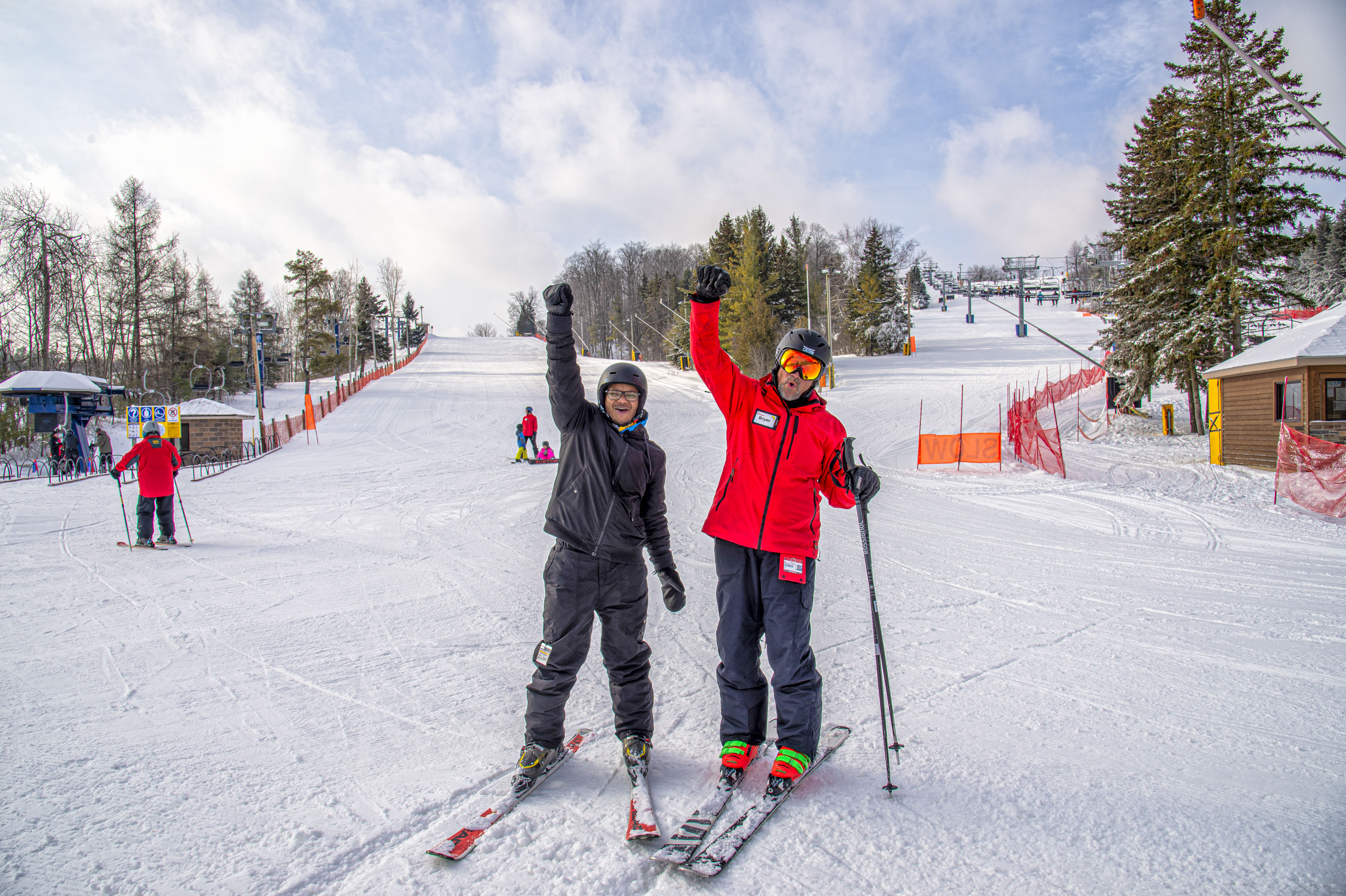 Instructor Bryan and his student standing at the base of Tenderfoot fist pumping and smiling. 