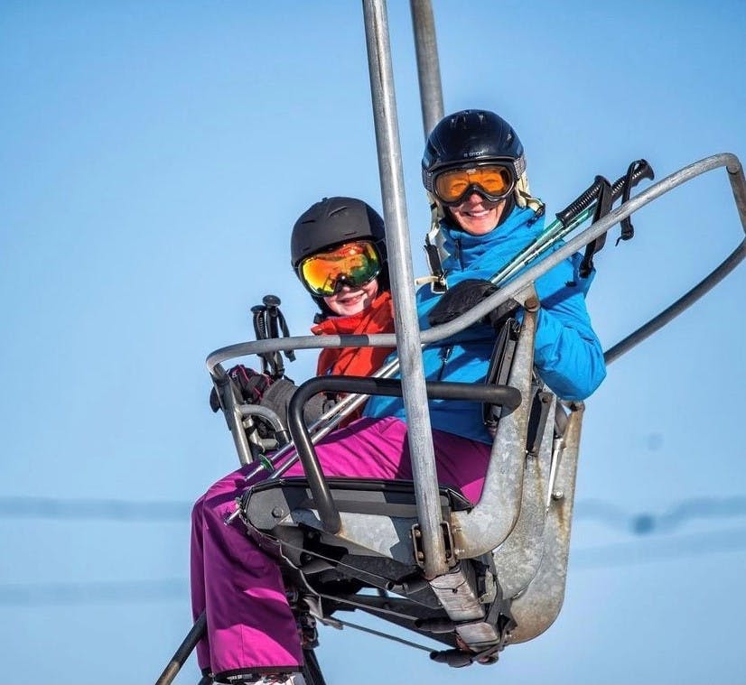 Mom and son riding chairlift to ski down the hill together 