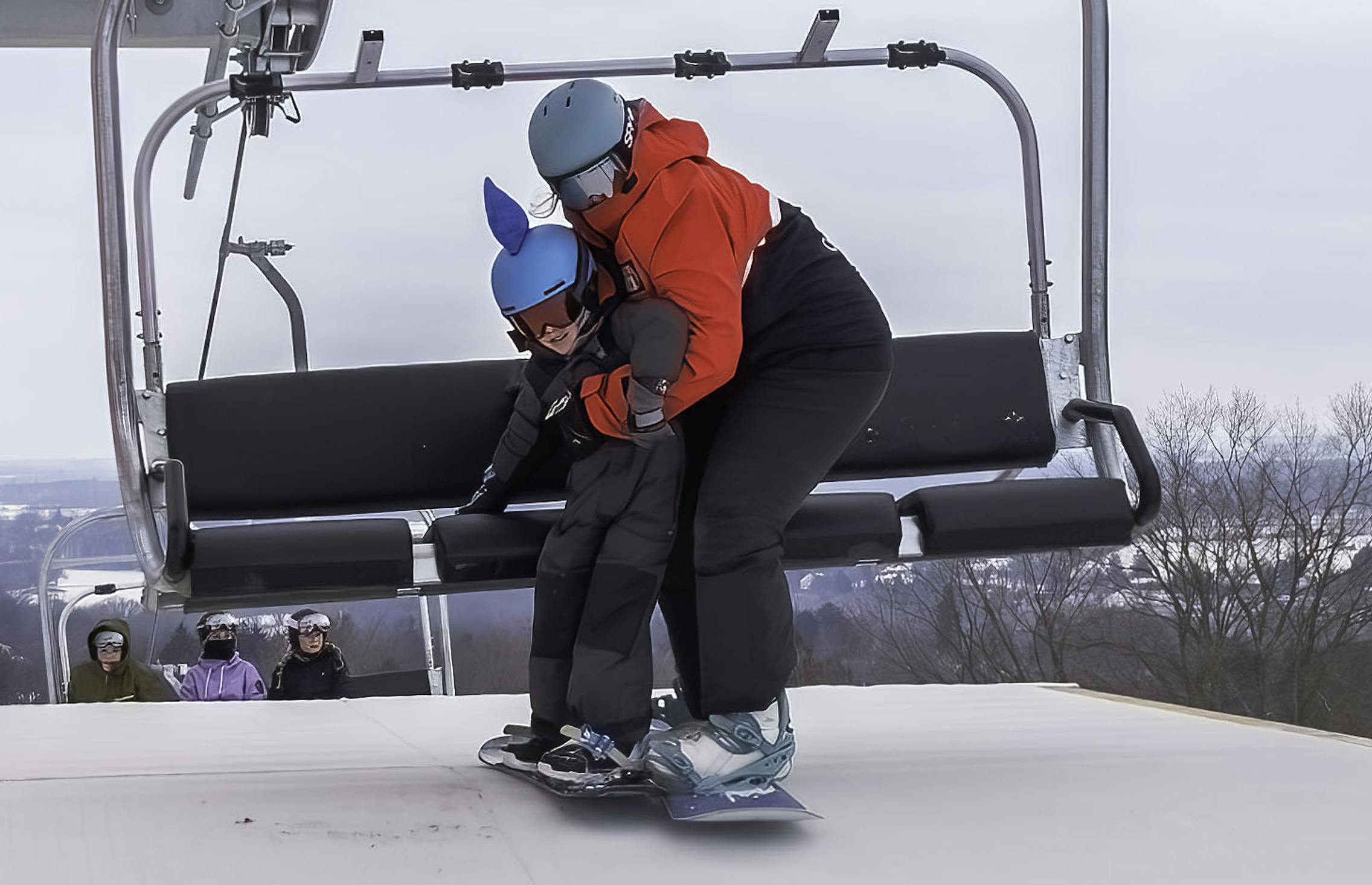 Snowboard instructor assisting student off Red Lift.
