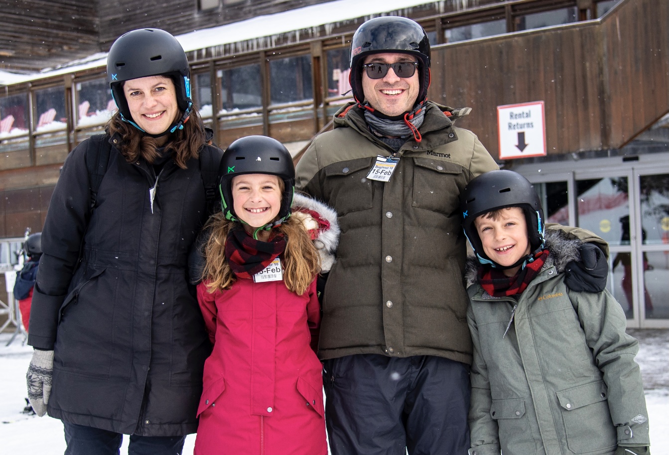 Family in snow suits posing in front of the chalet