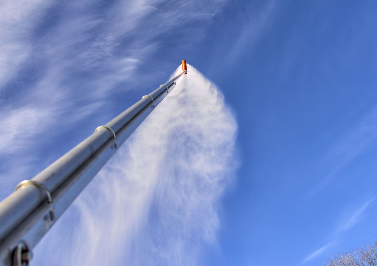 Bottom up image of a snow gun blowing snow. 