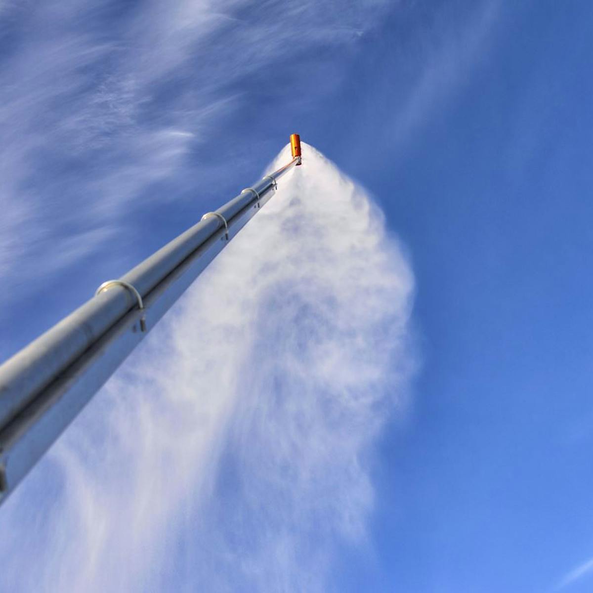 Bottom up image of a snow gun blowing snow. 