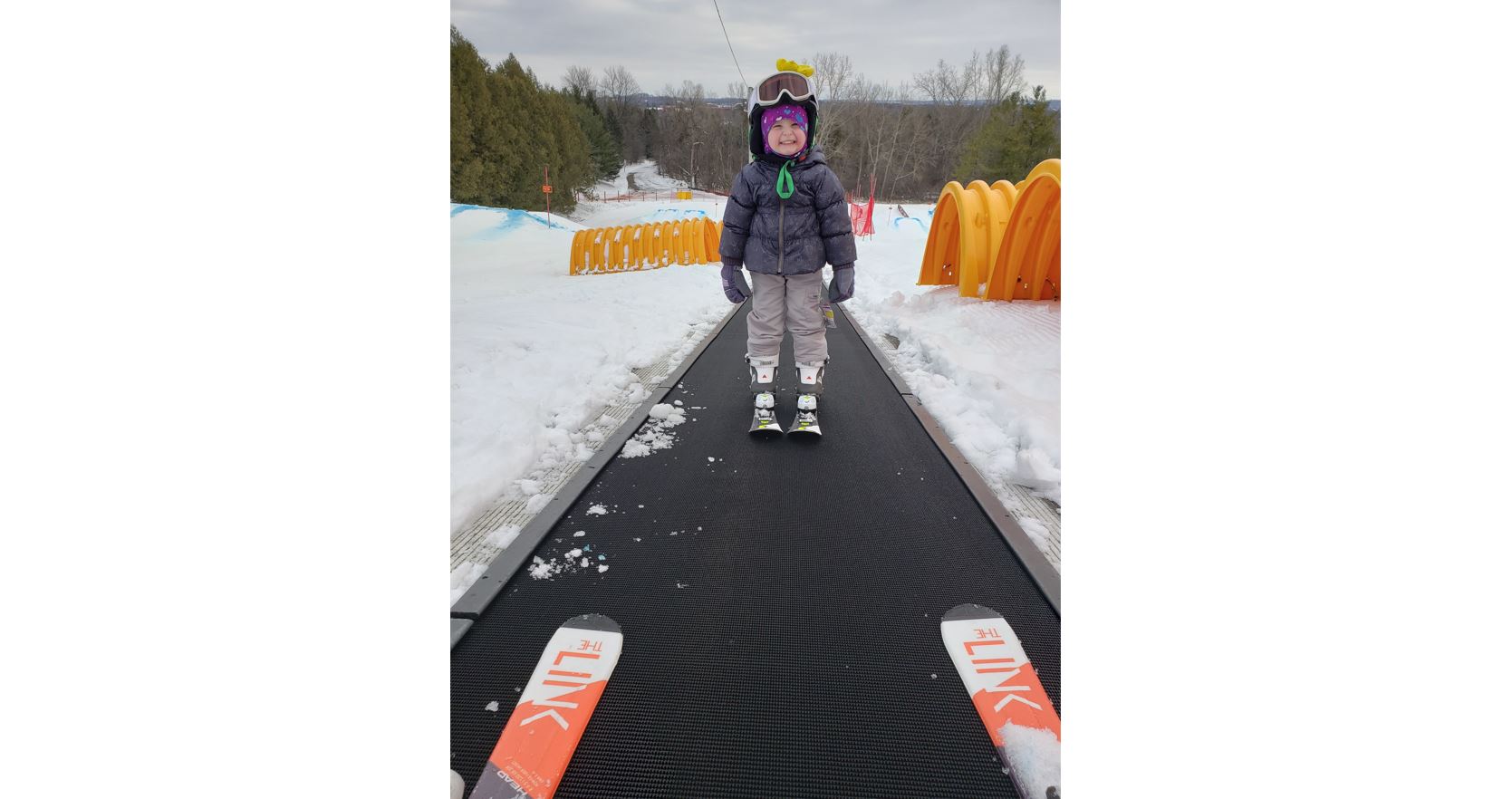 An excited young skier riding the magic carpet (surface lift). 