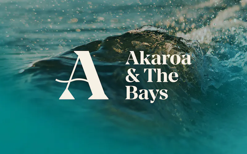 Akaroa & The Bays white logo over a blurred photo of waves crashing.