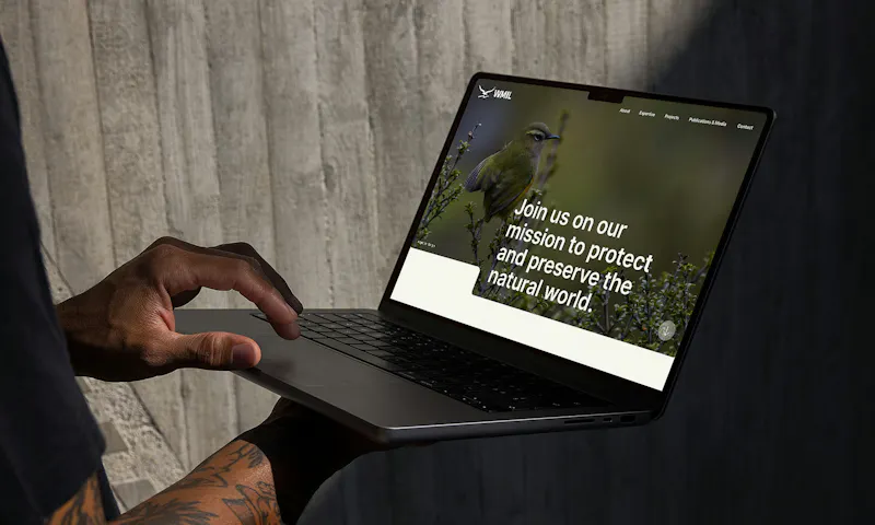 Man in a dark t-shirt holding a laptop that displays the WMIL website home page design.