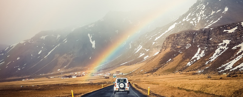 A beautiful landscape of mountains with a rainbow streaking across it. 
