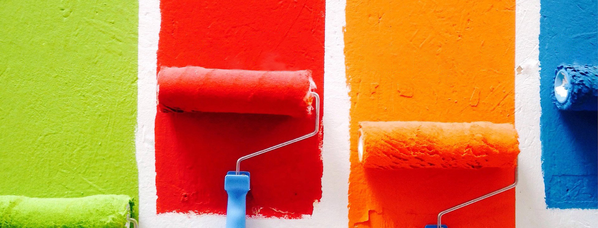 Rolling different coloured stripes of paint onto a white wall 