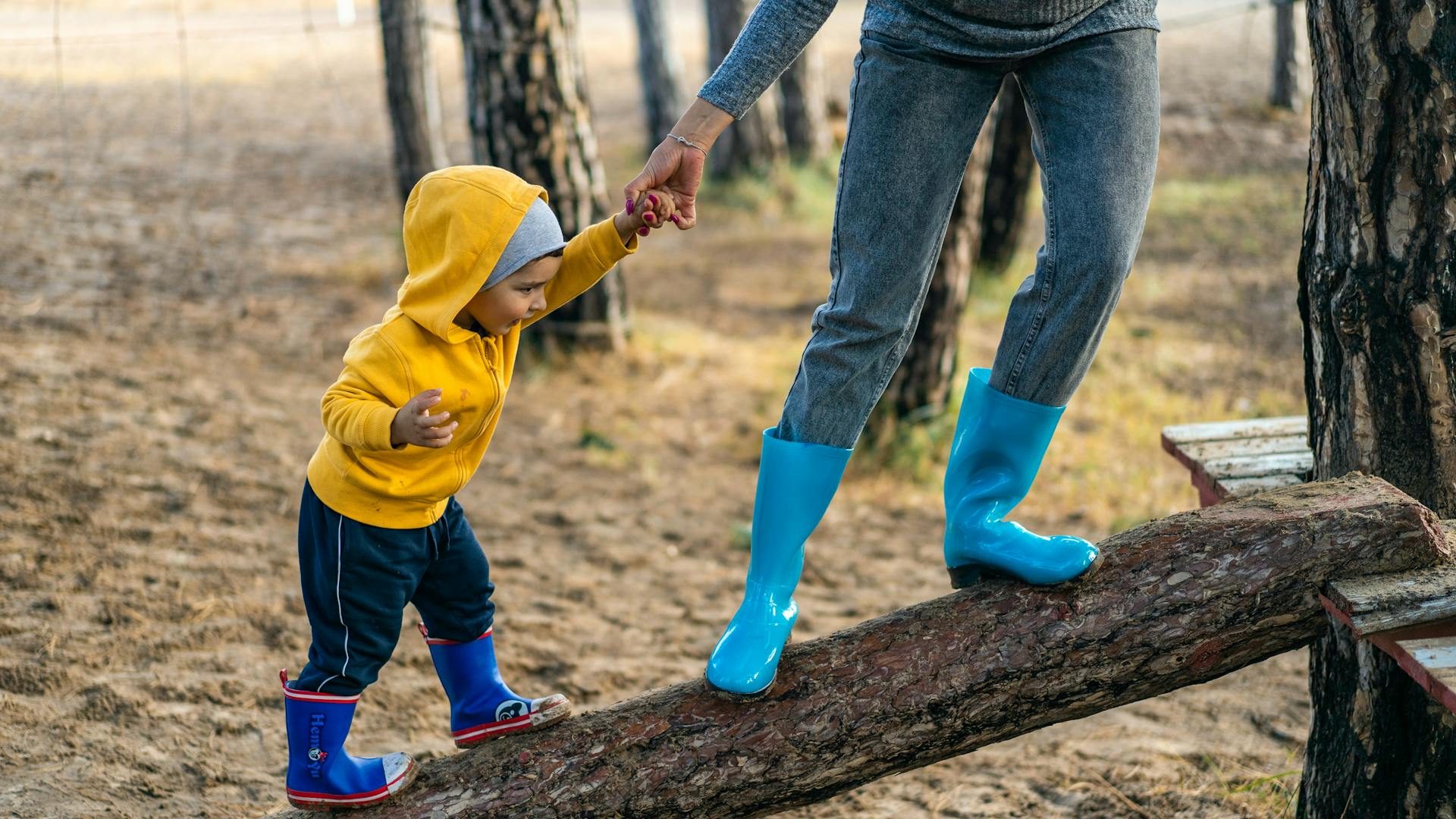 Mother leads a baby in boots up to a treehouse