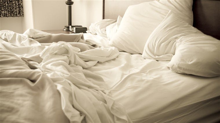 unmade king size bed with white linens