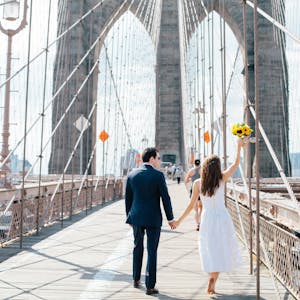 bride and groom walking across the Brooklyn bridge hand in hand