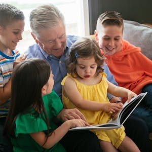 grandpa reading a book to his grandchildren