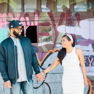 Couple poses in front of graffiti wall