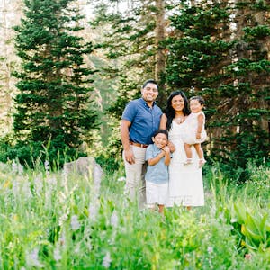 Family poses for family photos in a field of flowers and trees
