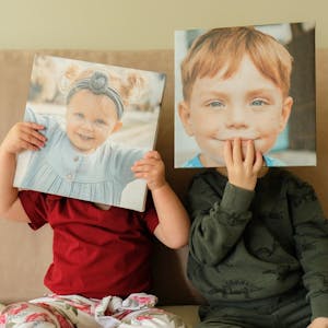 kids holding Chatbooks wall tiles up to their faces