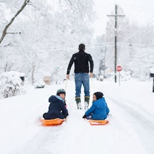 Dad pulling kids on sled