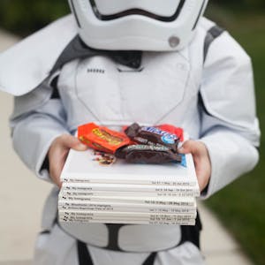 a child dressed up in Halloween costume with Chatbooks and candy in his hands