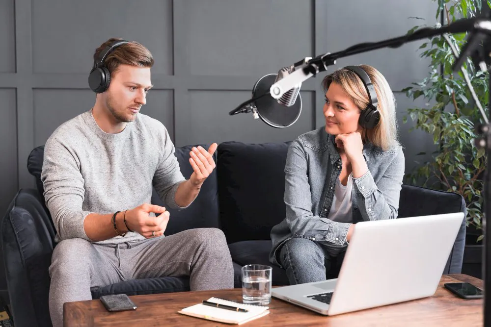 Two colleagues recording an instructional discussion beside a laptop