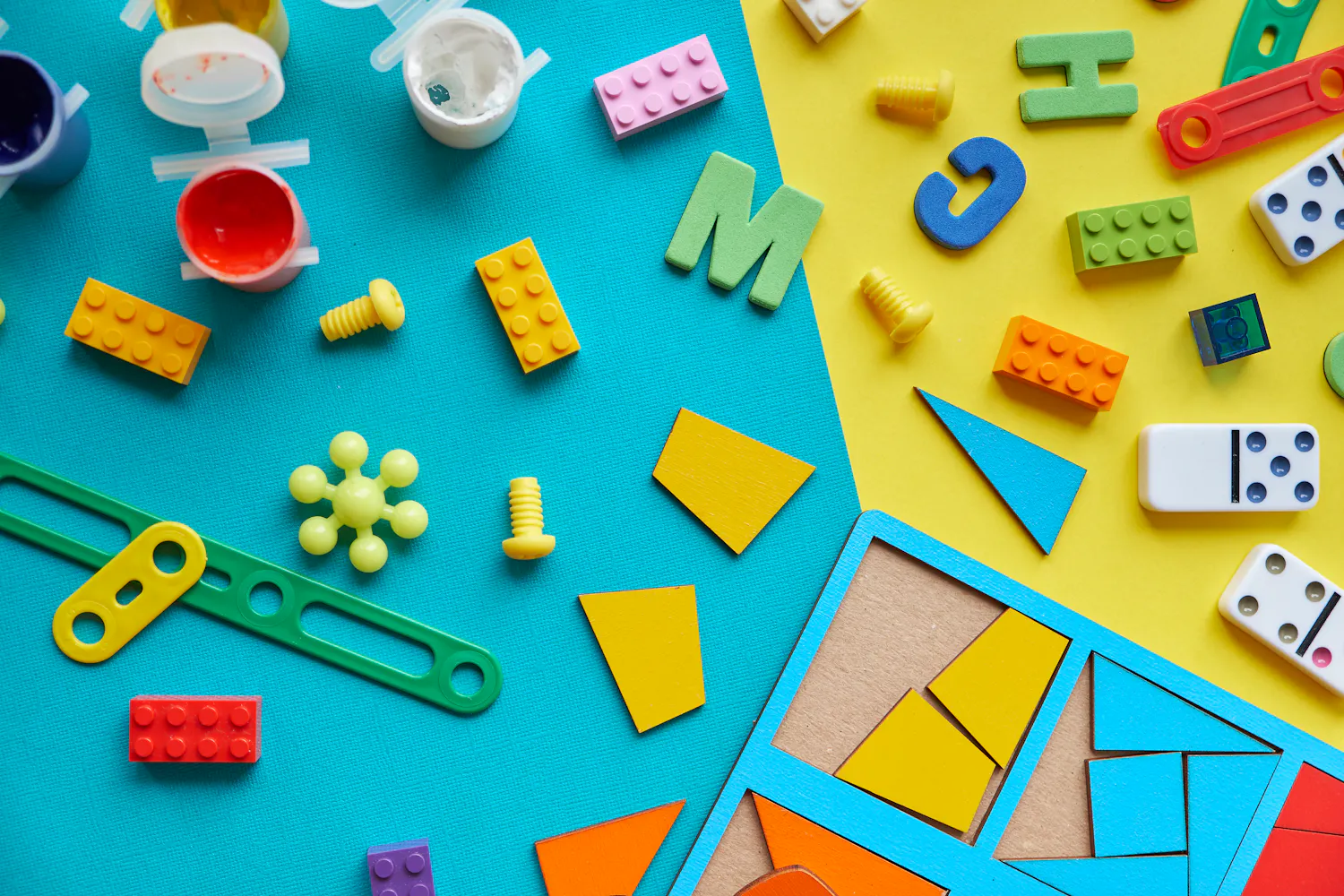 Différentes pièces détachées de jouets divers sur fond bleu et jaune.