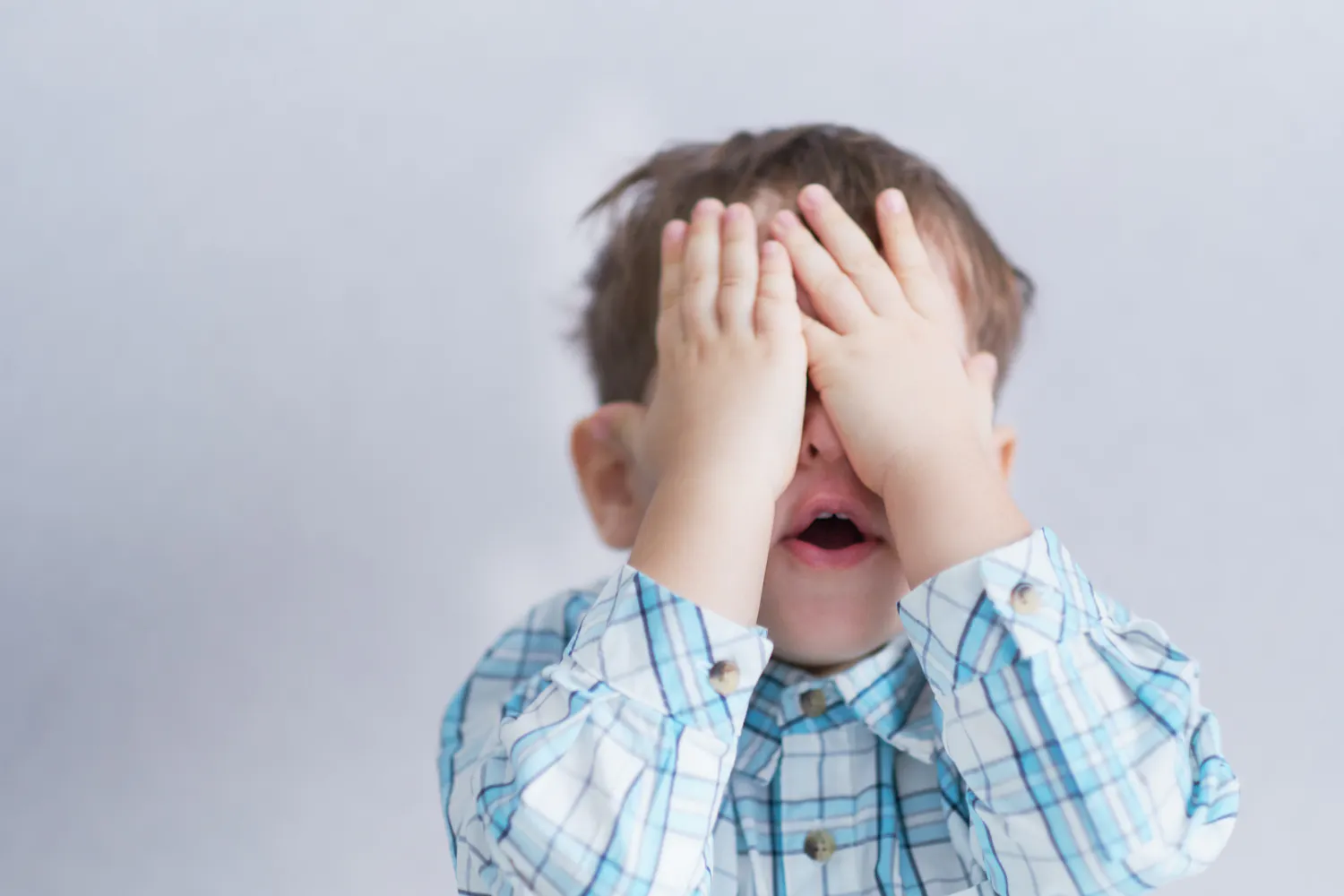 Enfant se cachant les yeux avec les mains.