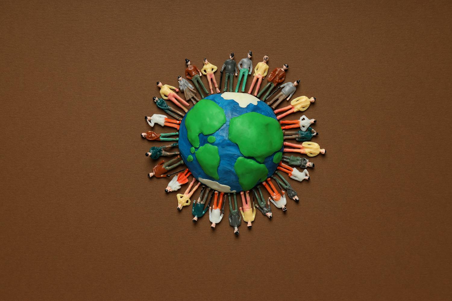 Planète Terre en pate à modeler avec des personnages autour sur fond marron.