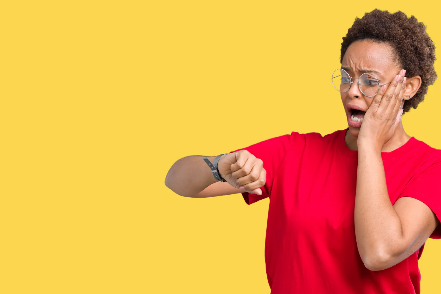 Femme habillée en rouge qui regarde sa montre en faisant une grimace sur fond jaune.