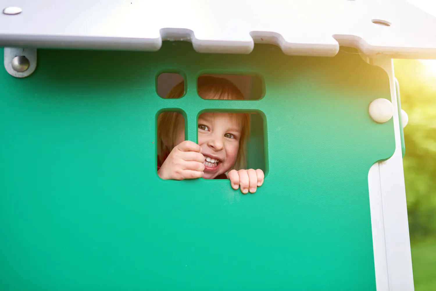 Enfant jouant dans une maison de jardin en plastique verte.