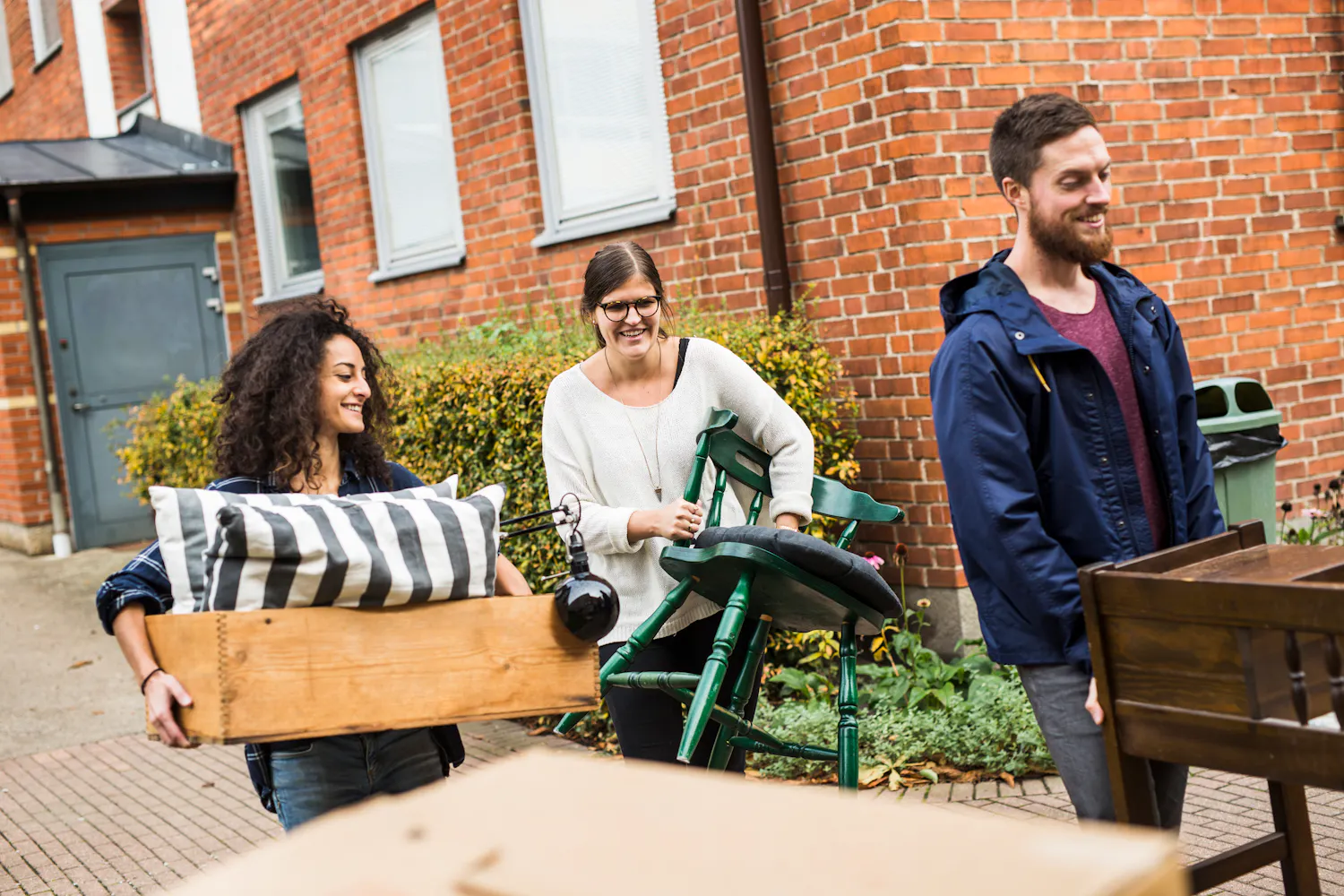 Trois amis en train de déménager et de porter des meubles.
