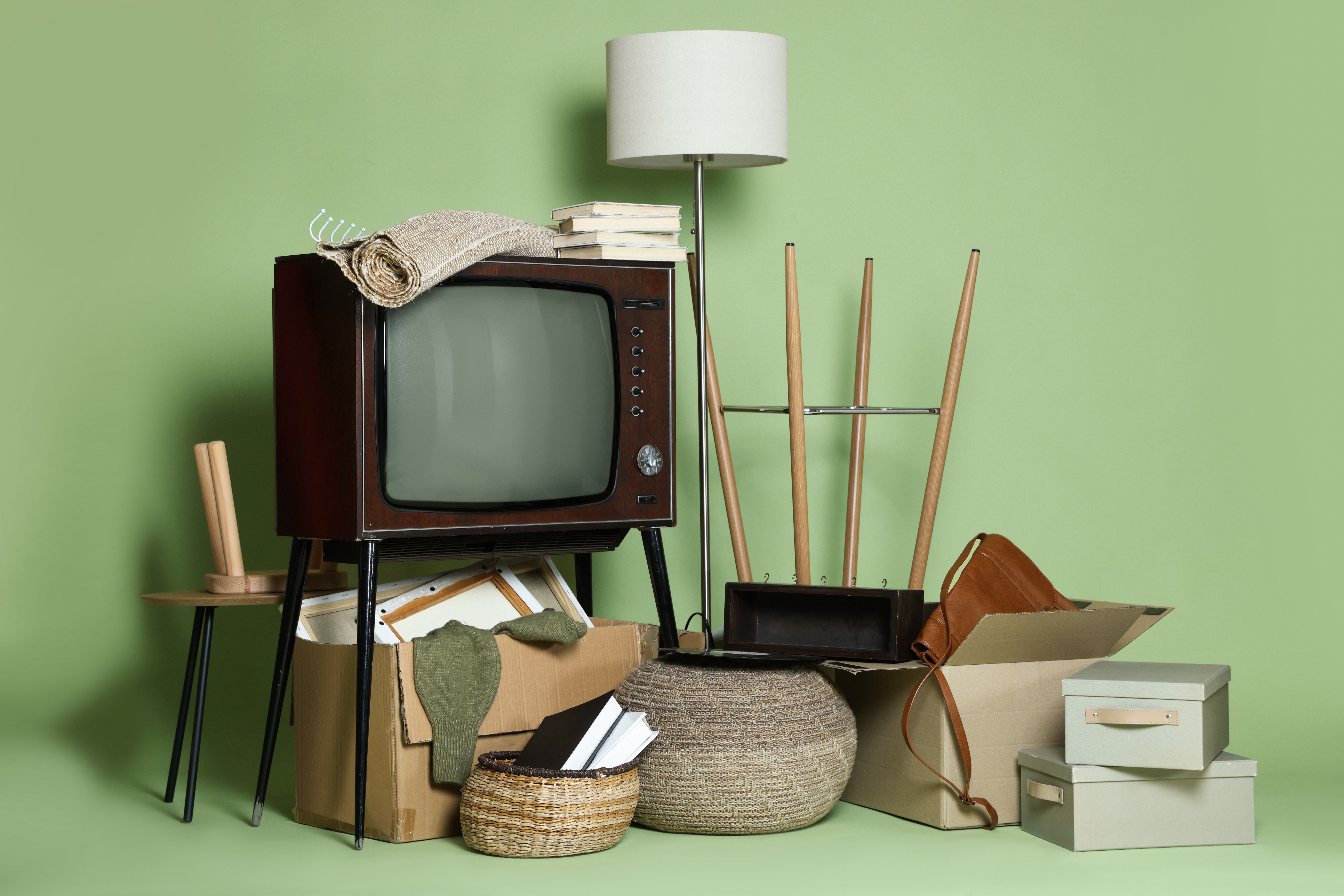 Divers objets de salon dont télévision, lampe et chaise sur fond vert. 