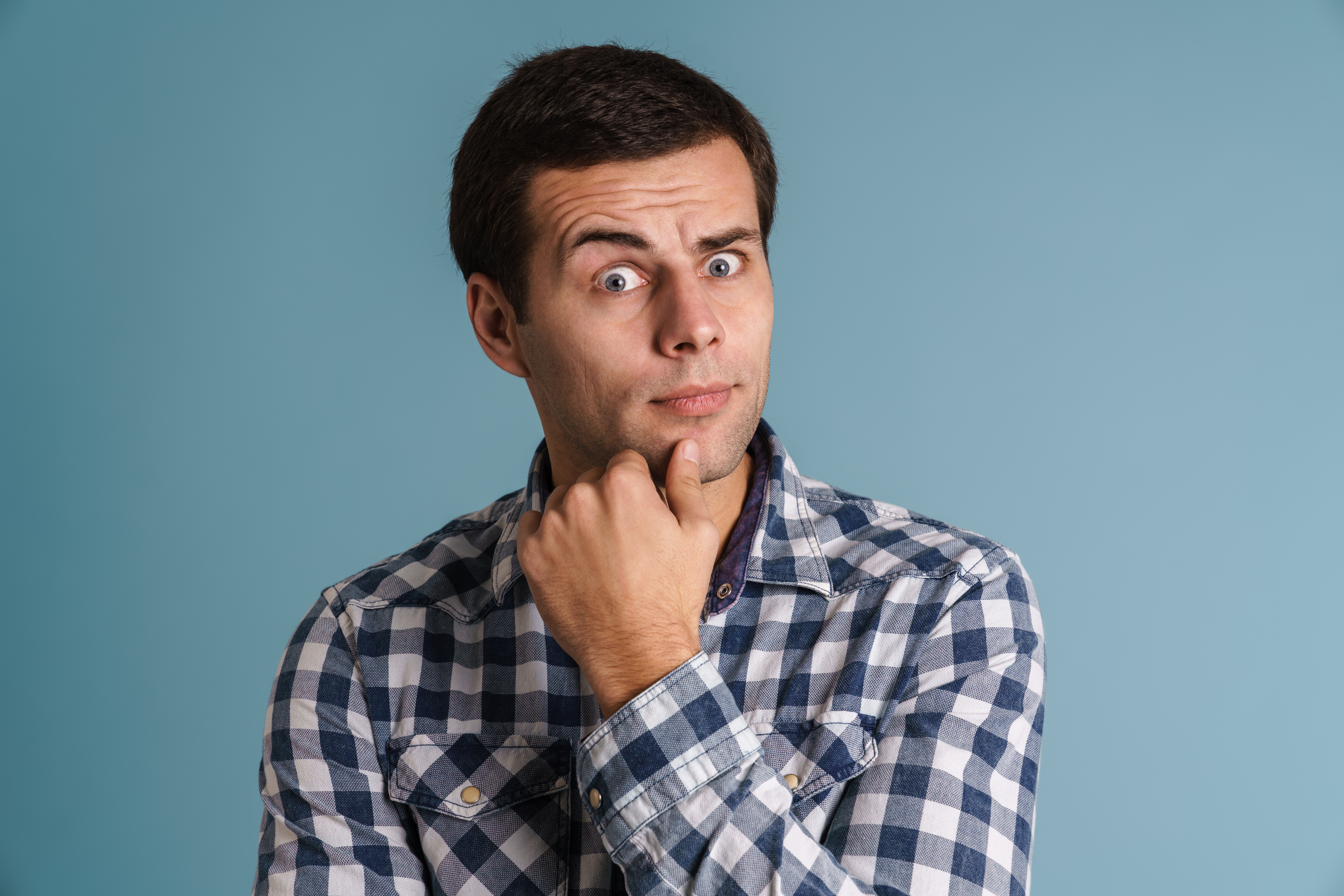 Homme se tenant le menton et se posant une question sur fond bleu.