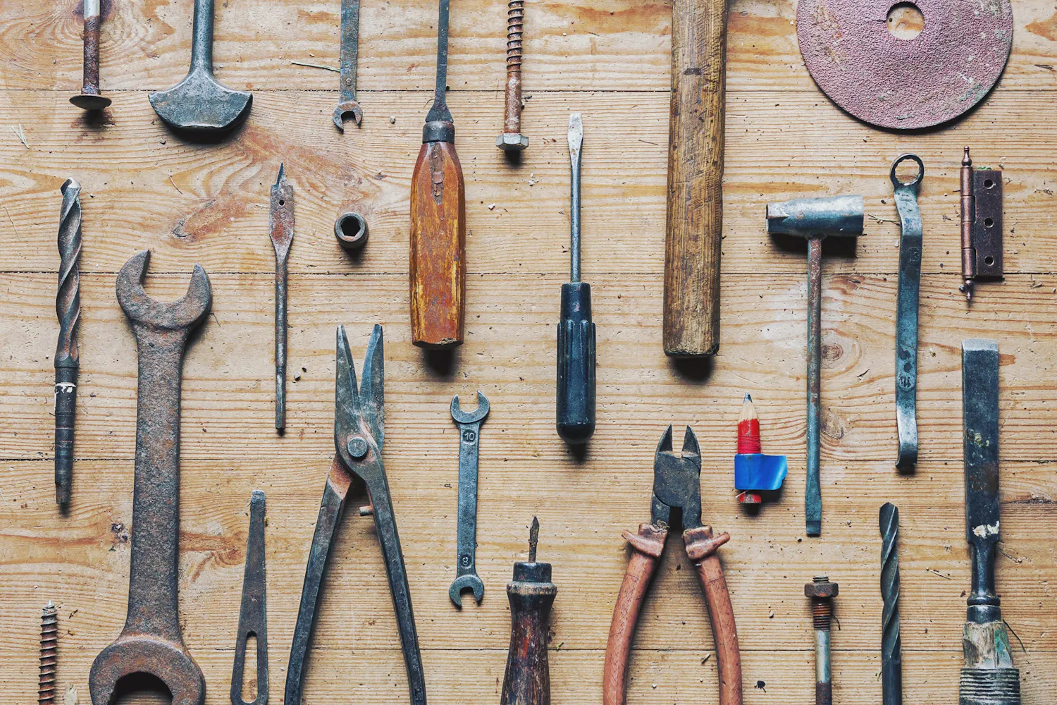 Lot de divers outils pour réparer et bricoler sur une planche de bois.