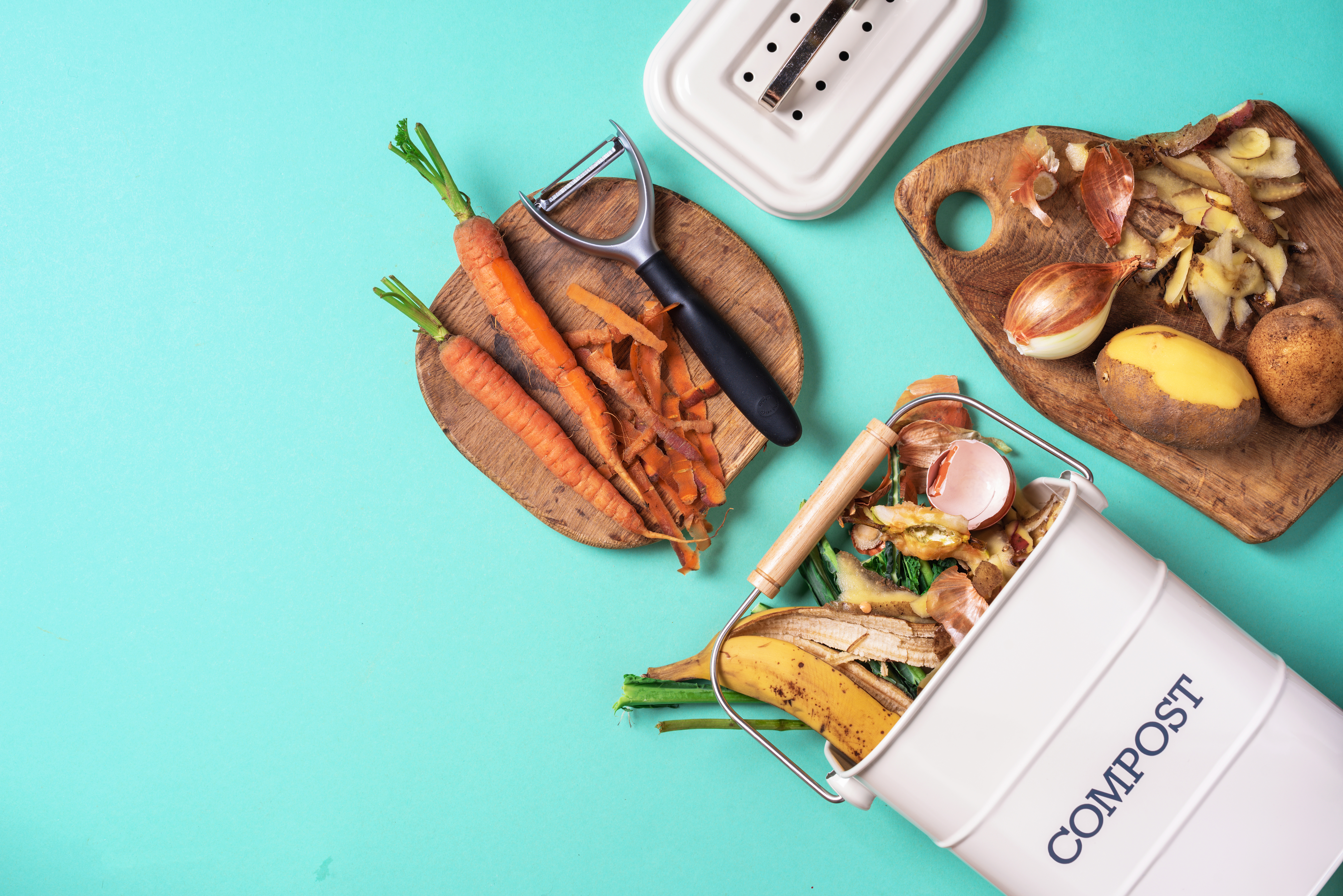 Divers légumes épluchés sur des  planches en bois et un composte sur fond bleu.