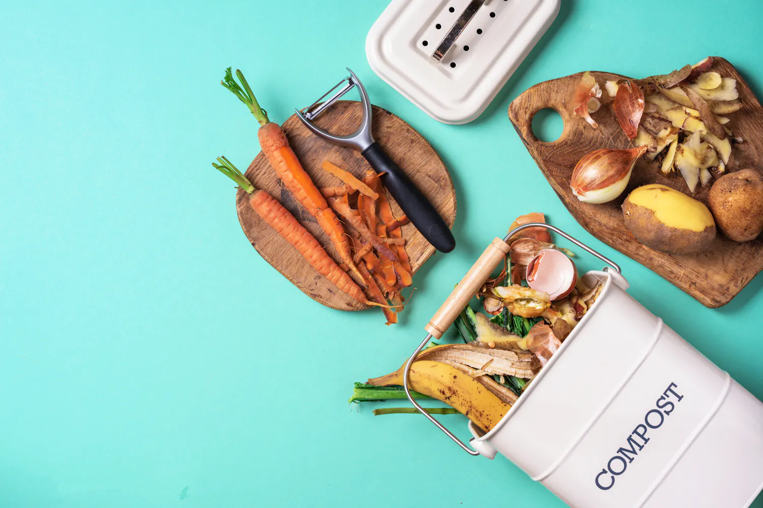 Divers légumes épluchés sur des planches en bois et un composte sur fond bleu.