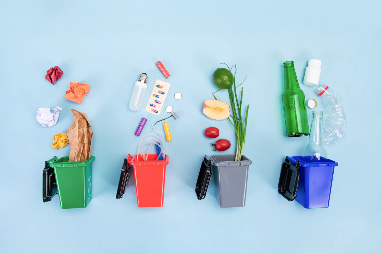 Quatre poubelles de couleurs différentes, avec des déchets triés pour chacune.